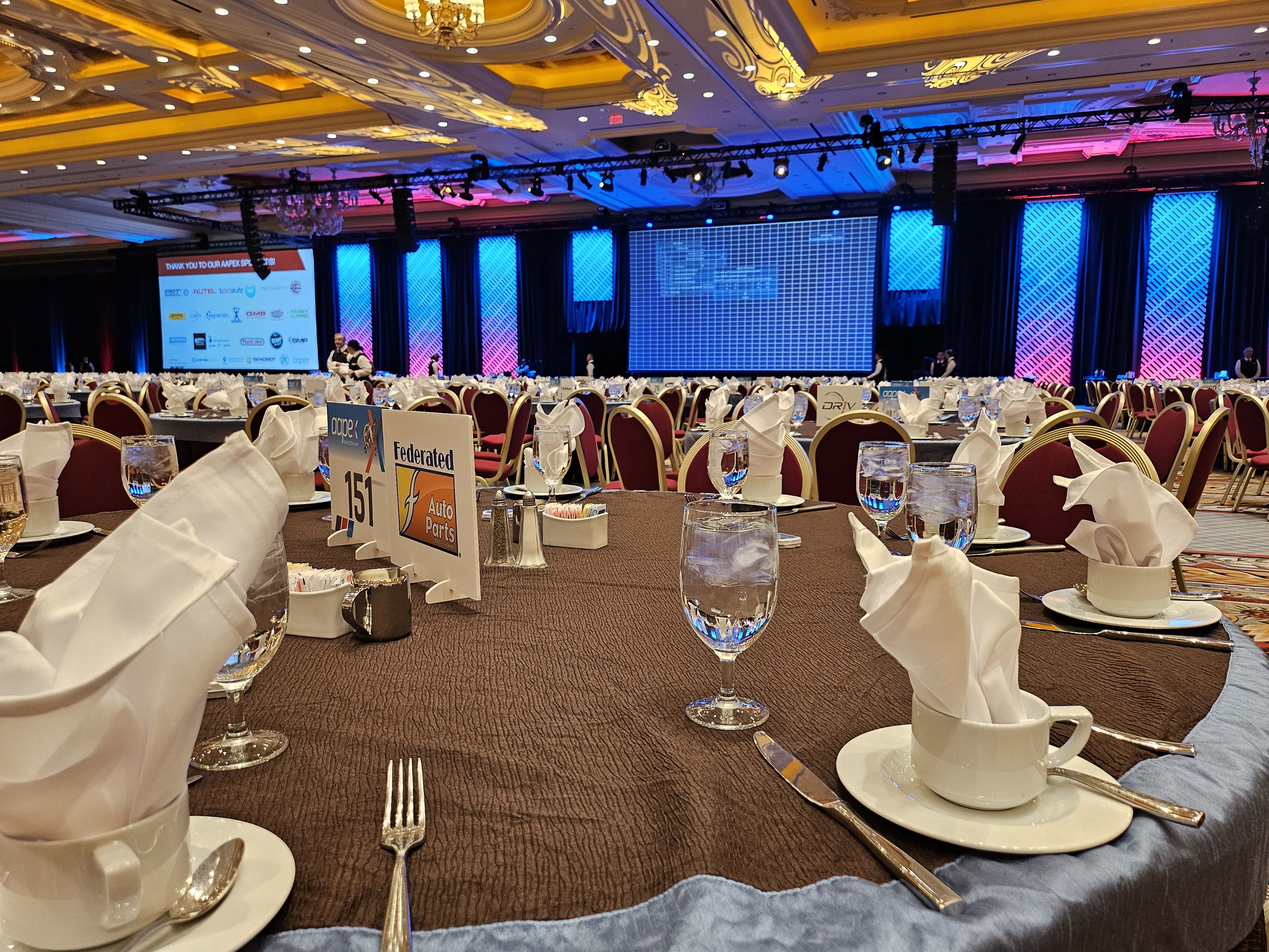 AAPEX banquet with formal table settings and LED stage backdrop